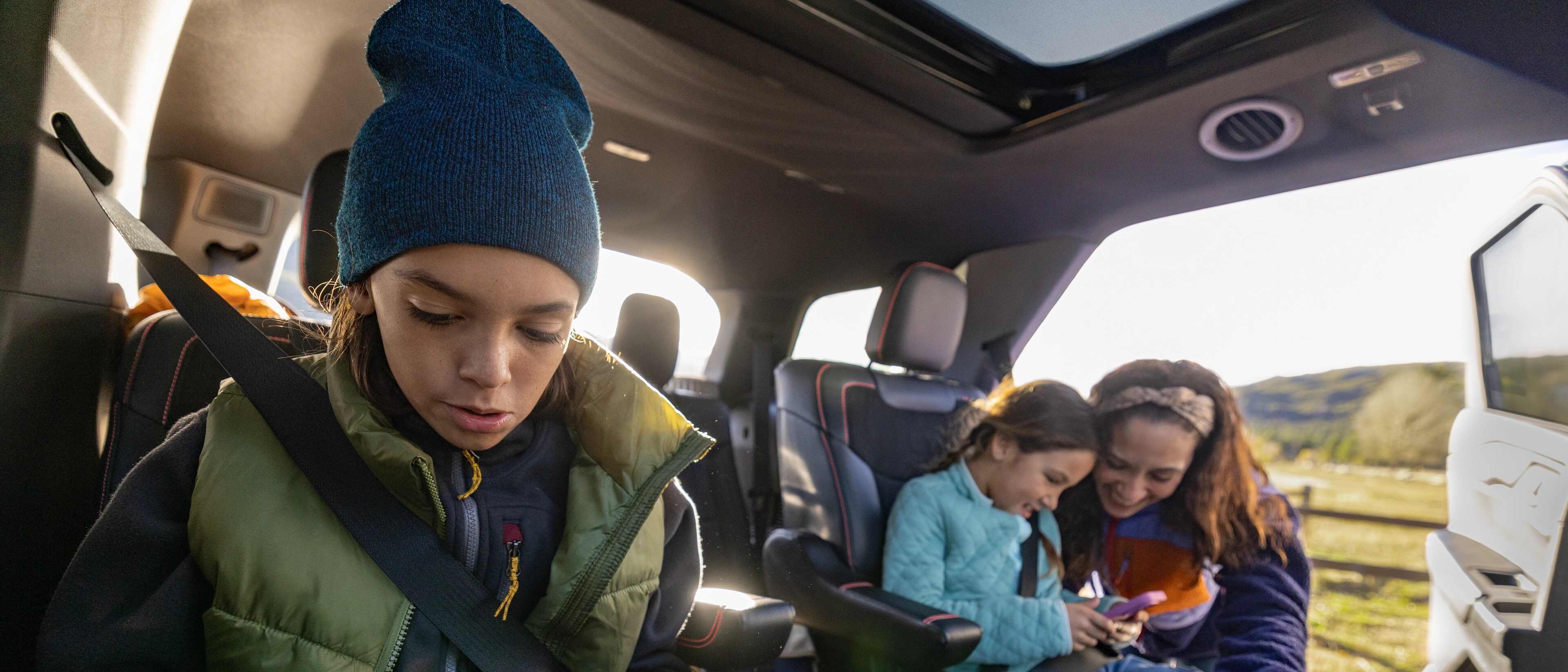 Une famille utilisant ses appareils, assise dans un VUS Ford Explorer® 2026 stationné