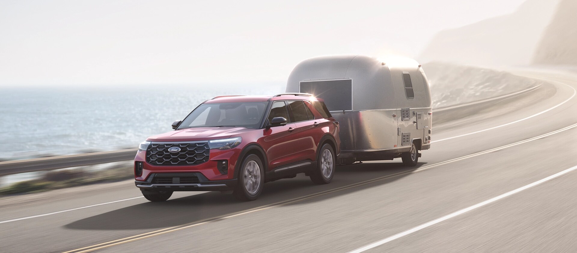 Un VUS Ford Explorer® 2026 tirant une caravane sur une autoroute côtière