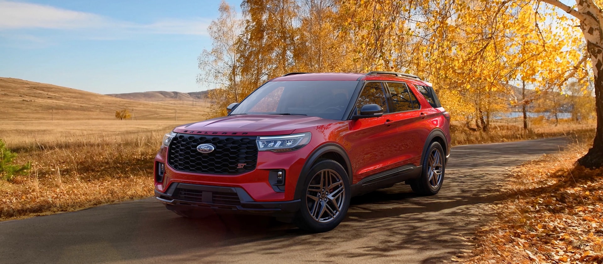 Un VUS Ford Explorer® 2026 sur une route à travers un champ à l’automne