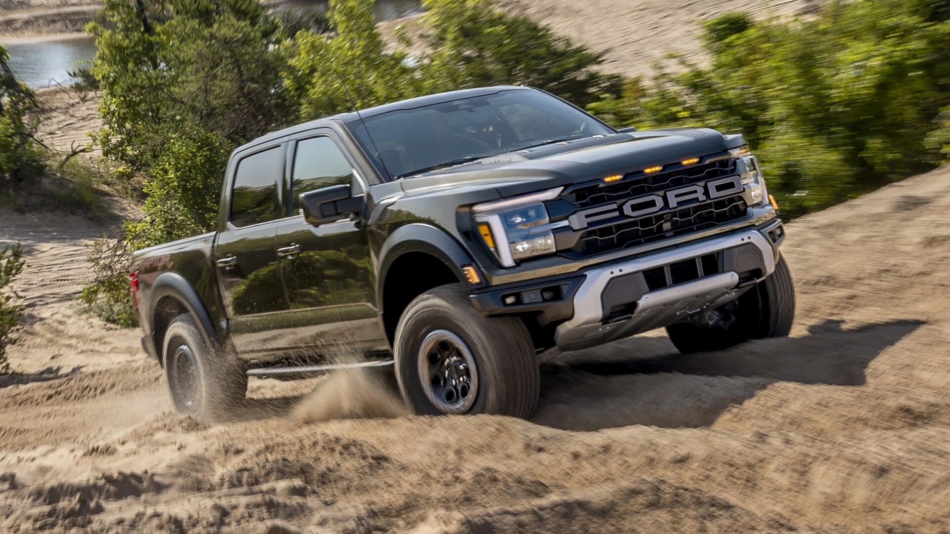 Camion Ford F-150® Raptor® 2025 en vert abri métallisé circulant sur un chemin rocheux dans le désert