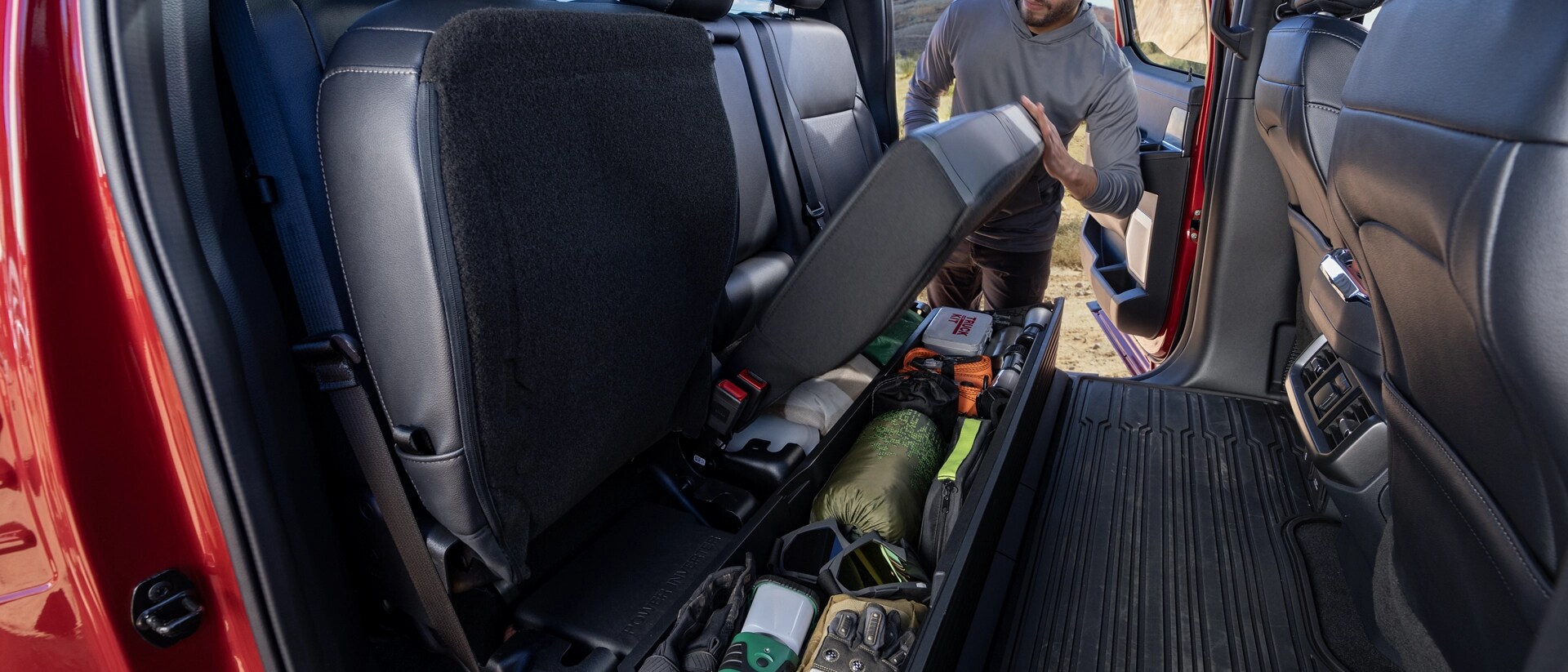 Une personne rabattant le siège arrière montrant la fonction de rangement sous le siège