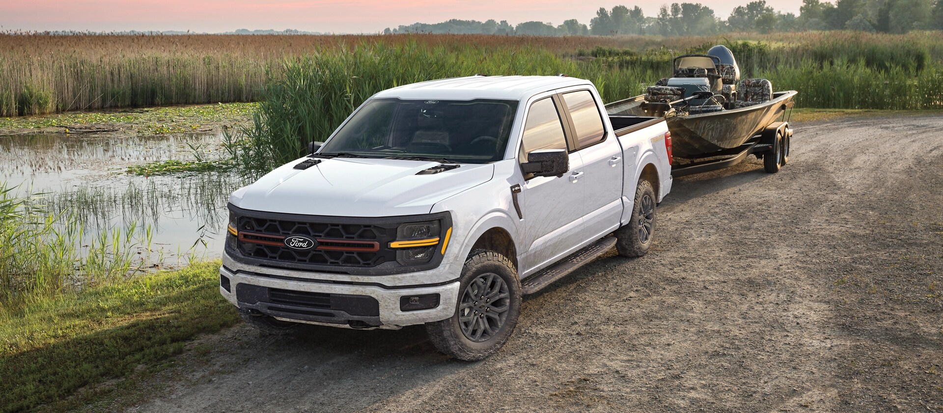 Camion Ford F-150® 2025 remorquant un bateau de pêche près d’un petit lac isolé