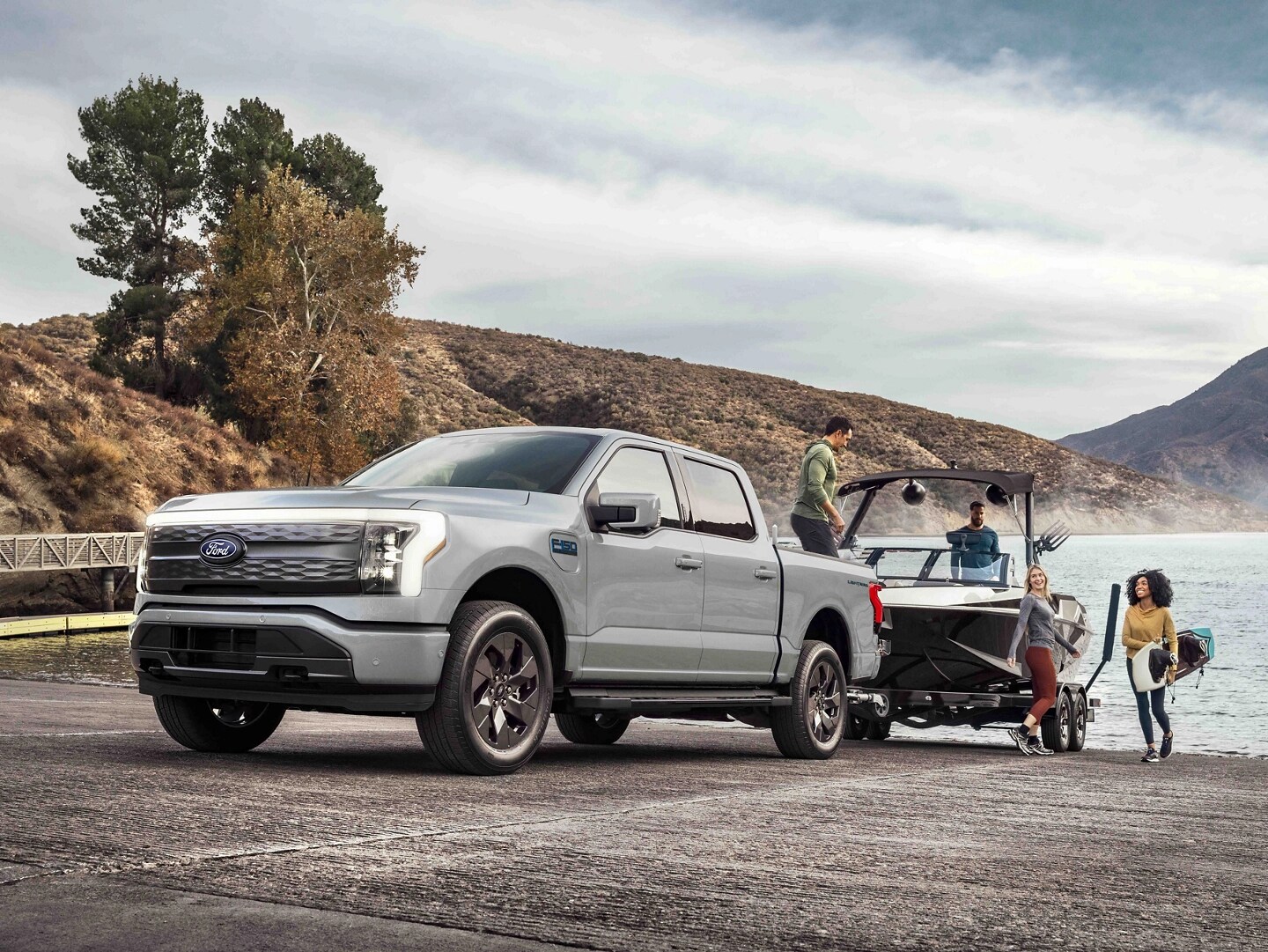 Un camion Ford F-150® Lightning® tirant un bateau sur une remorque hors d’un lac de montagne