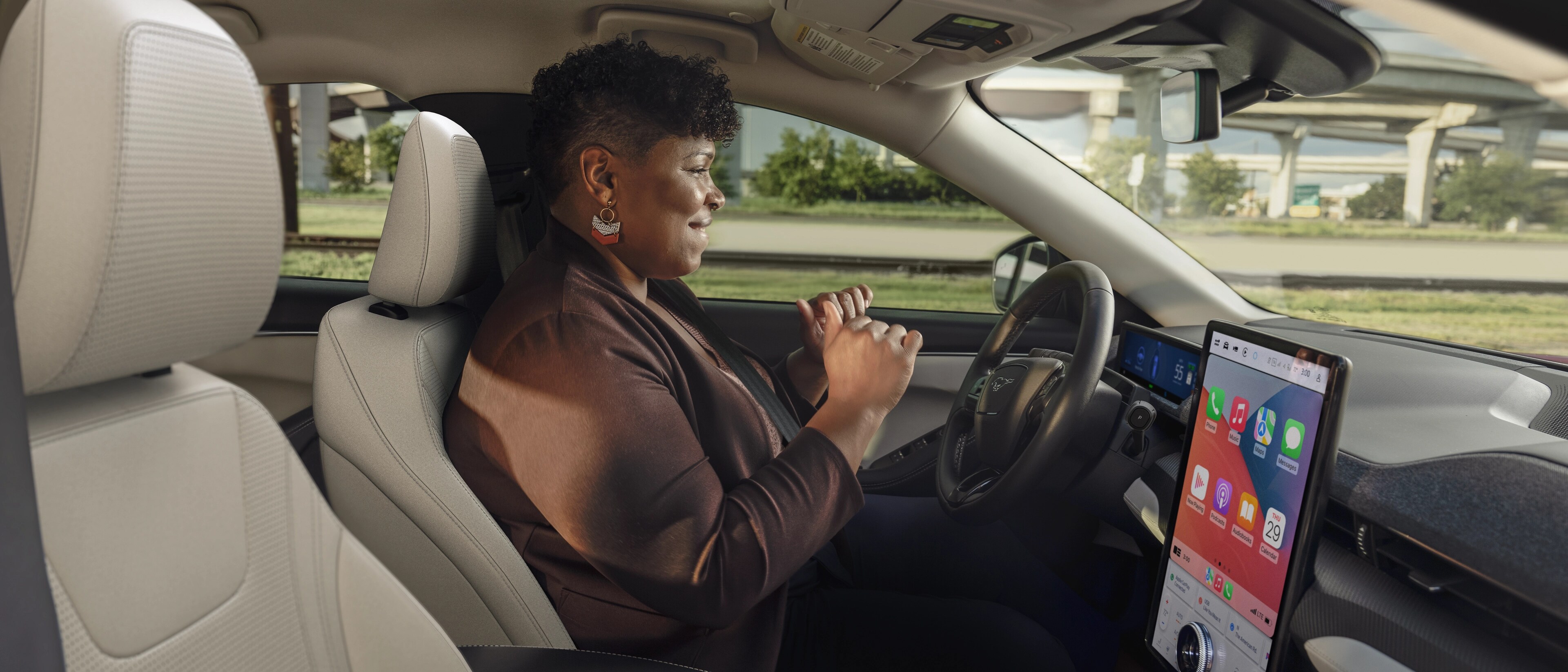 Femme utilisant la conduite mains libres Ford BlueCruise sur une autoroute dans une Ford Mustang Mach-E® 2025