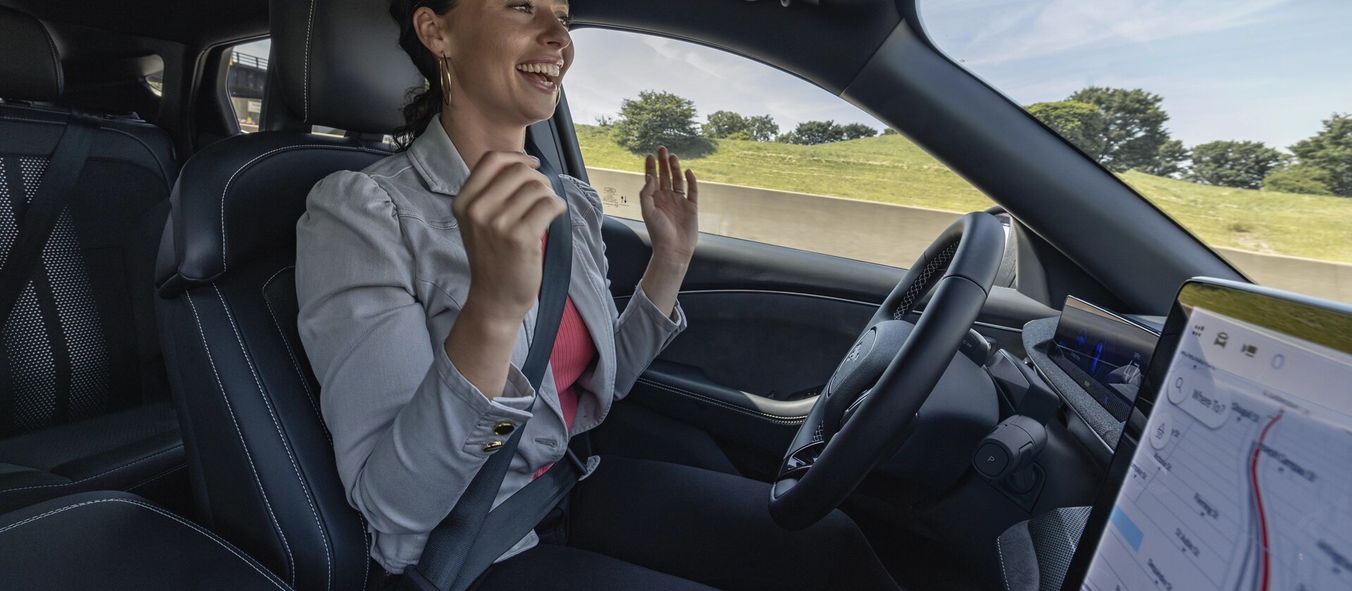 Une femme utilisant la conduite mains libres Ford BlueCruise sur une autoroute dans une Ford Mustang Mach-E® 2025