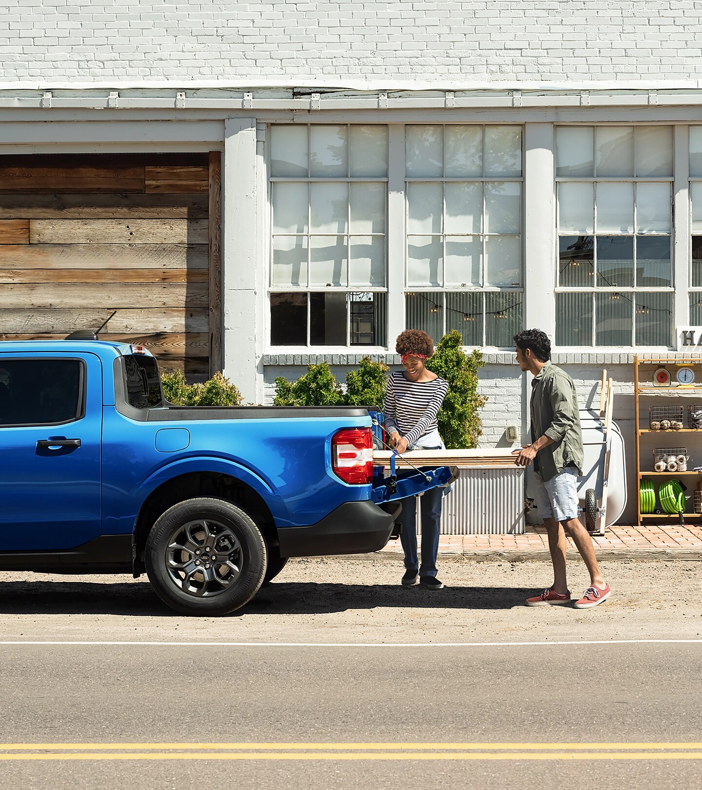 Deux personnes chargeant des feuilles de contreplaqué dans la caisse de chargement d’une camionnette Ford Maverick® 2025