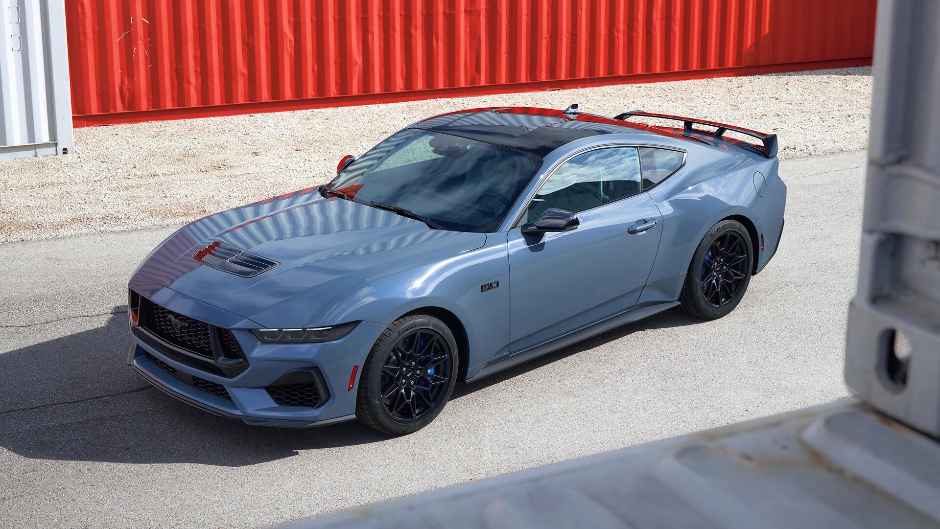 Ford Mustang® GT Coupé 2025 avec ensemble Mustang Nite Pony stationné près de conteneurs d’expédition