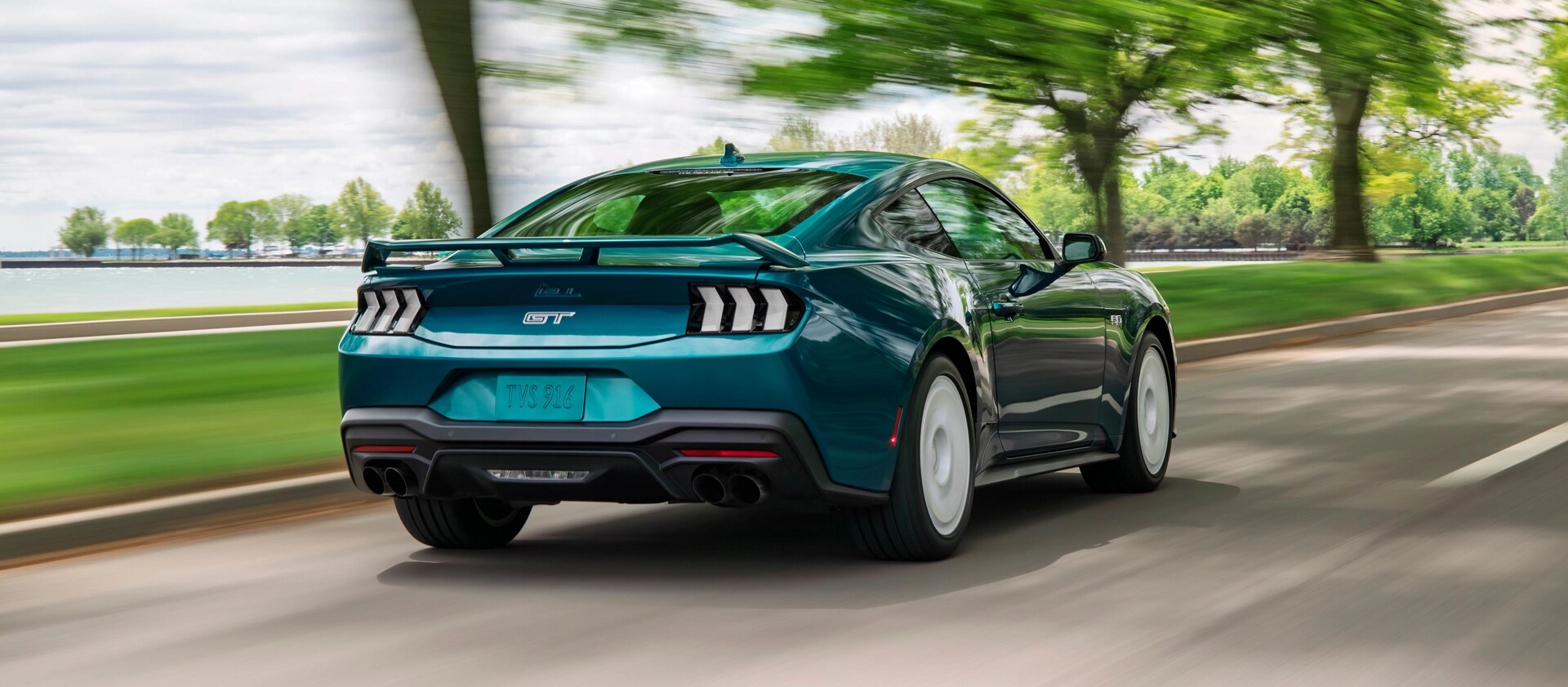 Vue arrière d’une Ford Mustang® GT Premium 2026 avec ensemble FX en option circulant près d’un lac