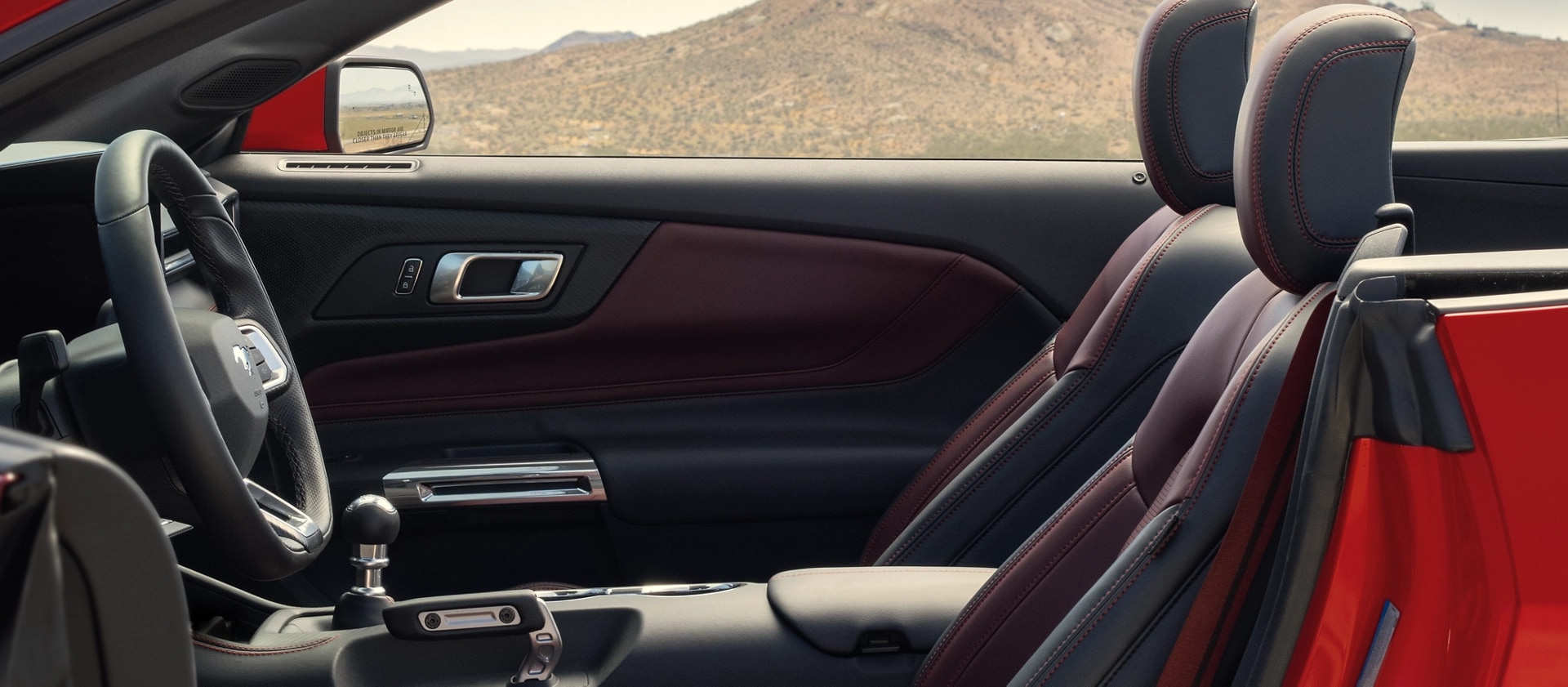 Ford Mustang® 2026 décapotable stationnée avec la portière du côté conducteur ouverte montrant l’intérieur rouge carmin en option