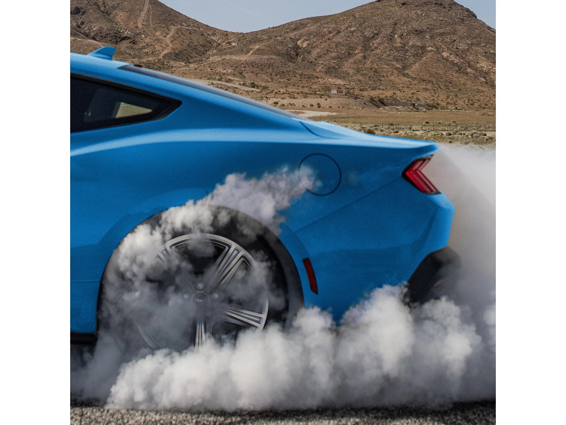 Une Ford Mustang® EcoBoost® 2026 en Bleu accrocheur tournant sur elle-même avec de la fumée sortant du pneu arrière.