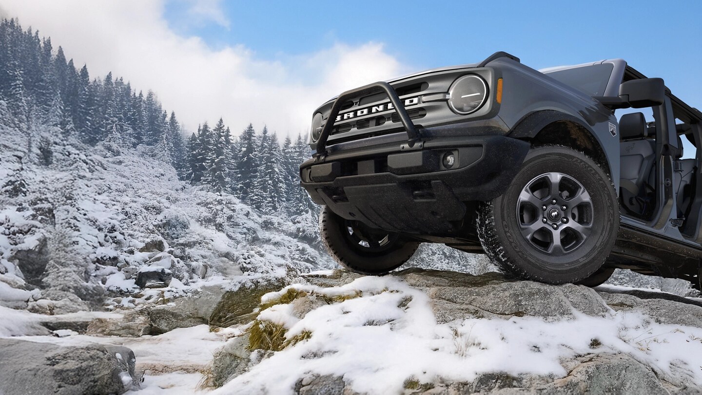 Un Bronco 2025, portes ouvertes, garé sur une montagne enneigée.