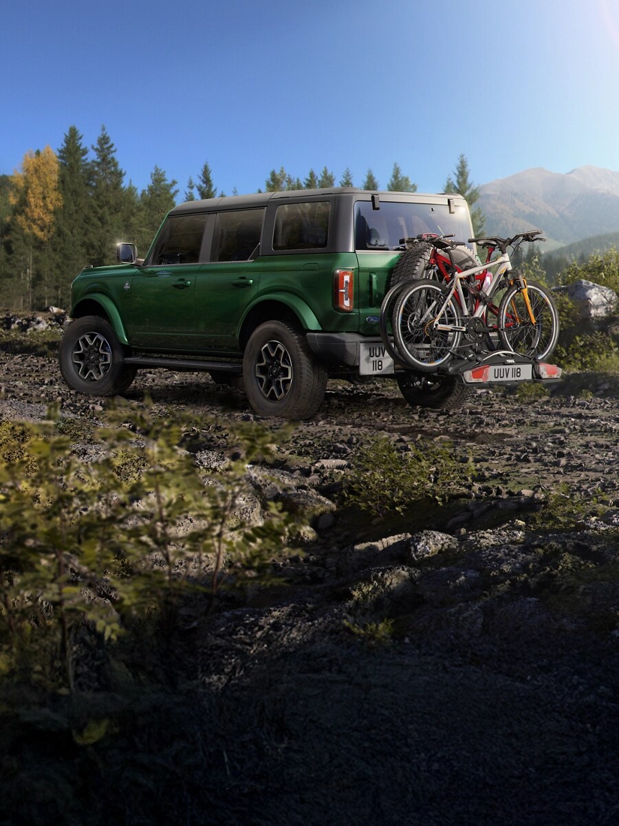 Bronco avec vélos montés à l'arrière, garé sur un sentier.