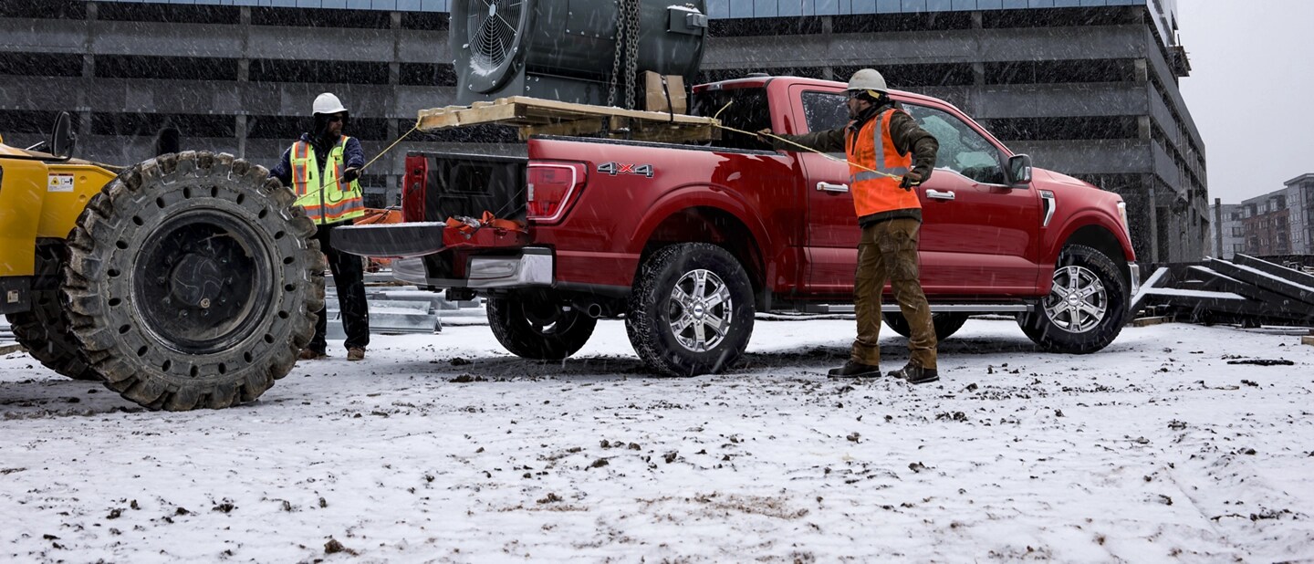 Deux hommes chargent du matériel lourd dans la caisse d'un camion F 150.