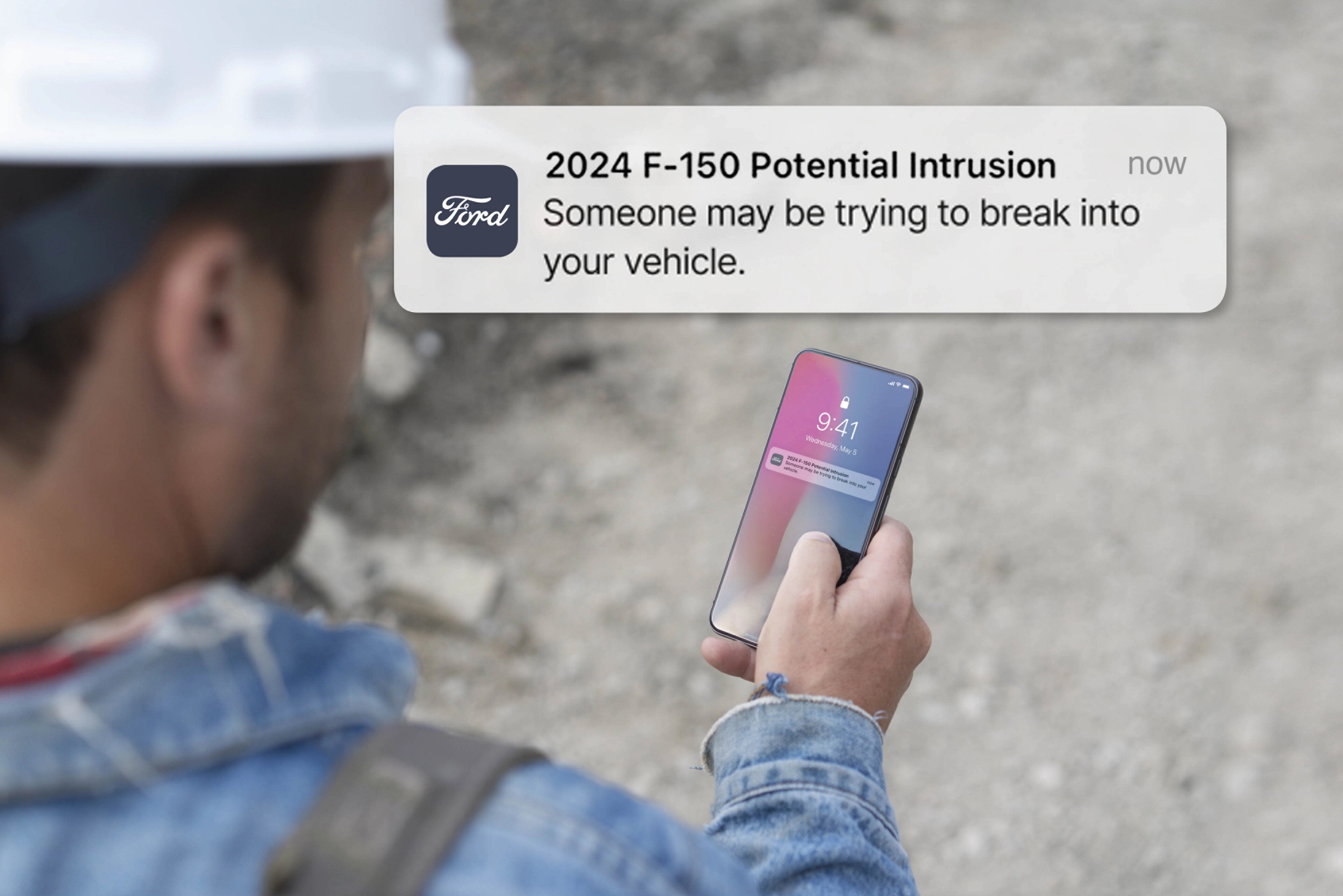 Personne tenant un téléphone intelligent affichant une notification. Superposition du texte qui se lit comme suit : Intrusion potentielle! Quelqu’un peut essayer de pénétrer dans votre véhicule.