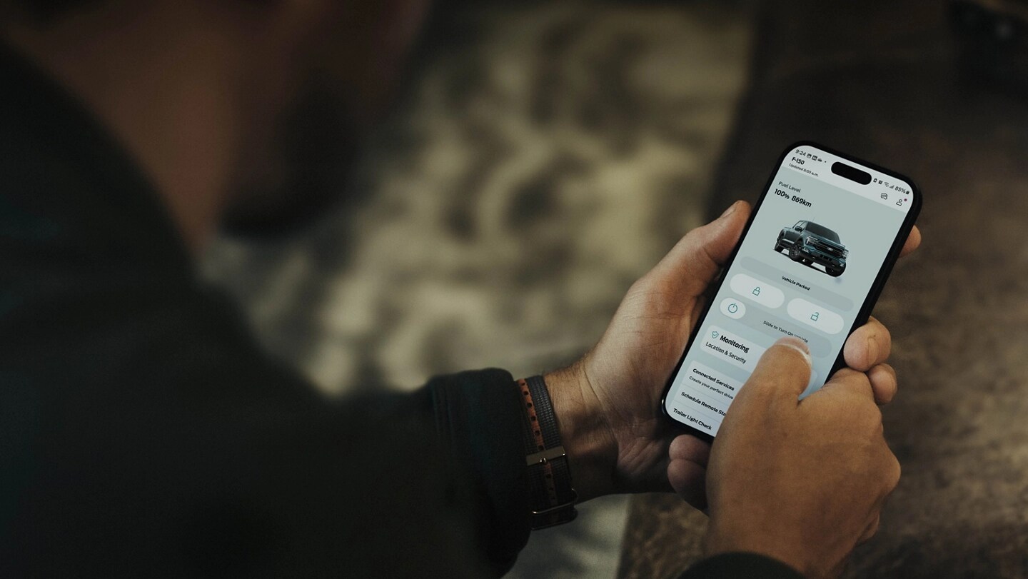 Personne tenant un téléphone intelligent affichant un écran dans l’application Ford.