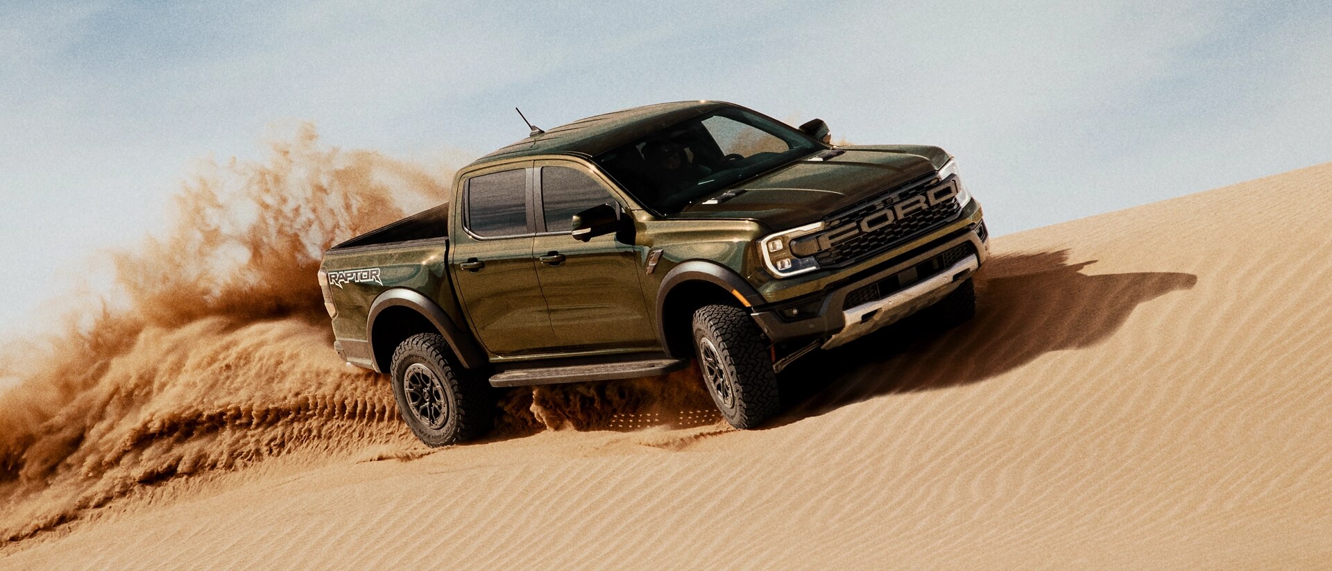 Un modèle Ranger® Raptor® 2025 circulant sur une dune de sable et projetant du sable