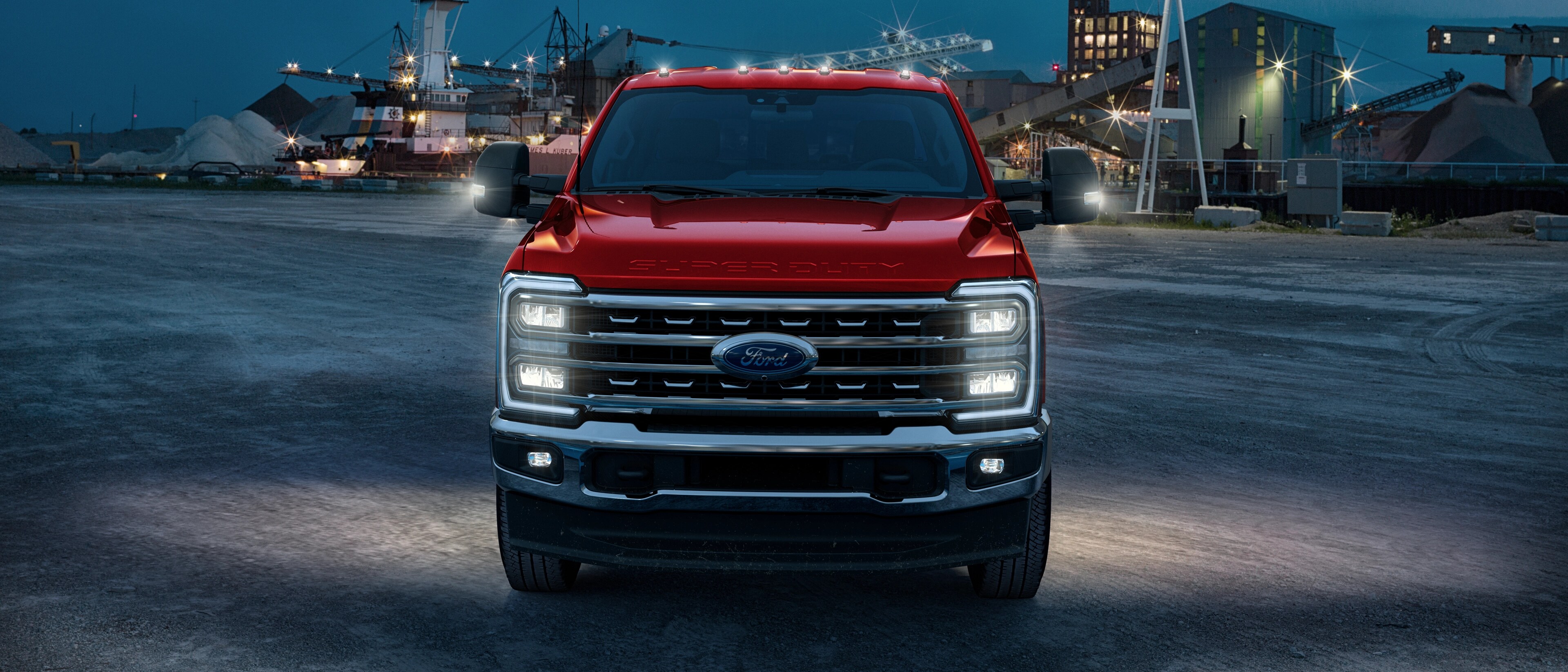 Ford Super Duty® F-450® 2026 avec l’ensemble hors route Tremor® stationné sur un chantier de construction au crépuscule avec ses lumières allumées