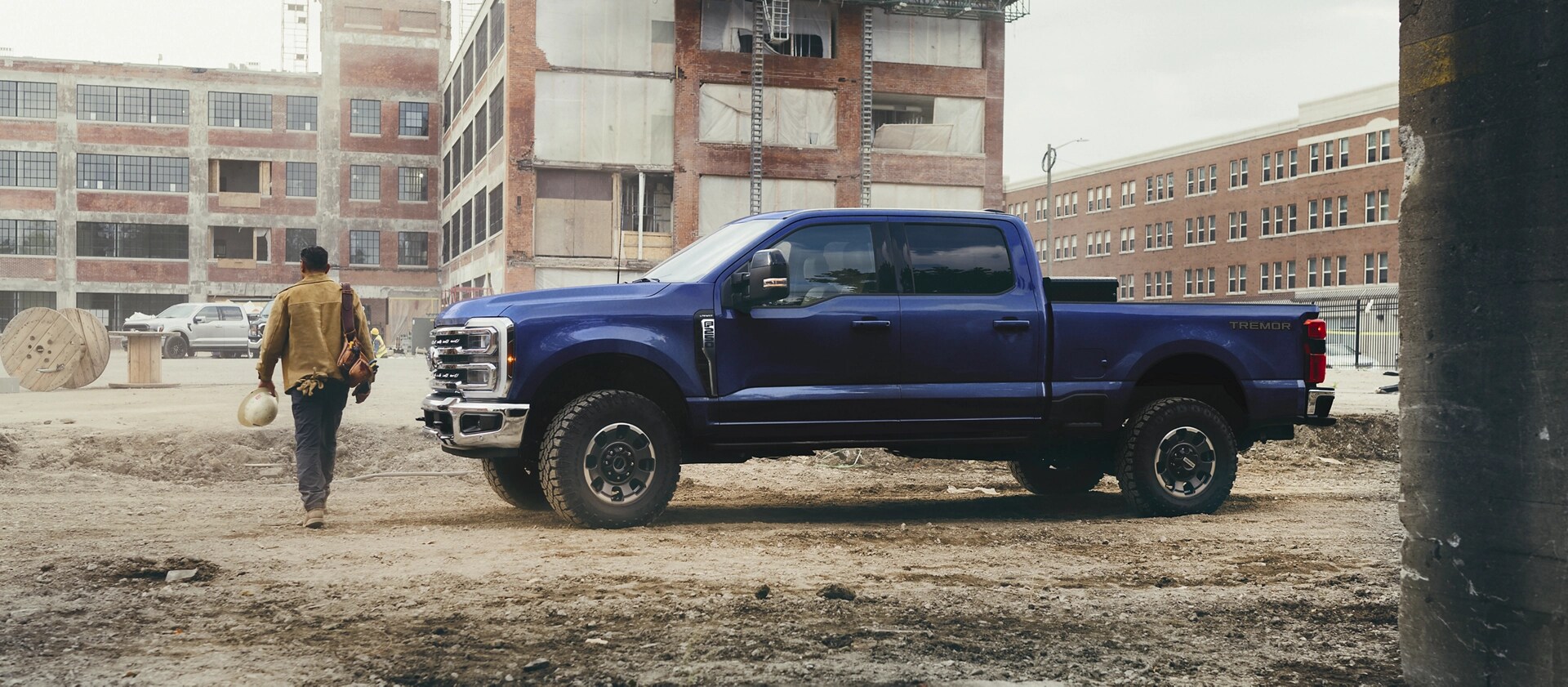 Une personne s’éloignant de son modèle Ford Super Duty® F-250® Lariat® 2026 en bleu argon sur un chantier de construction