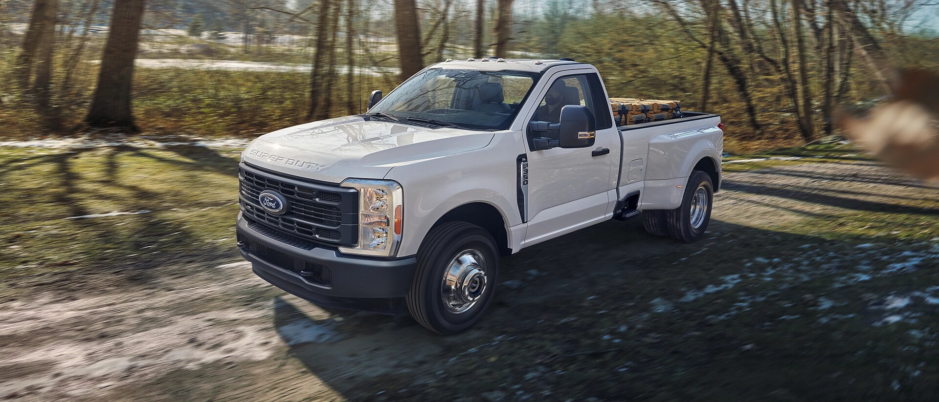 Ford Super Duty® F-350® XL 2026 circulant sur une route de terre avec une caisse de camion pleine