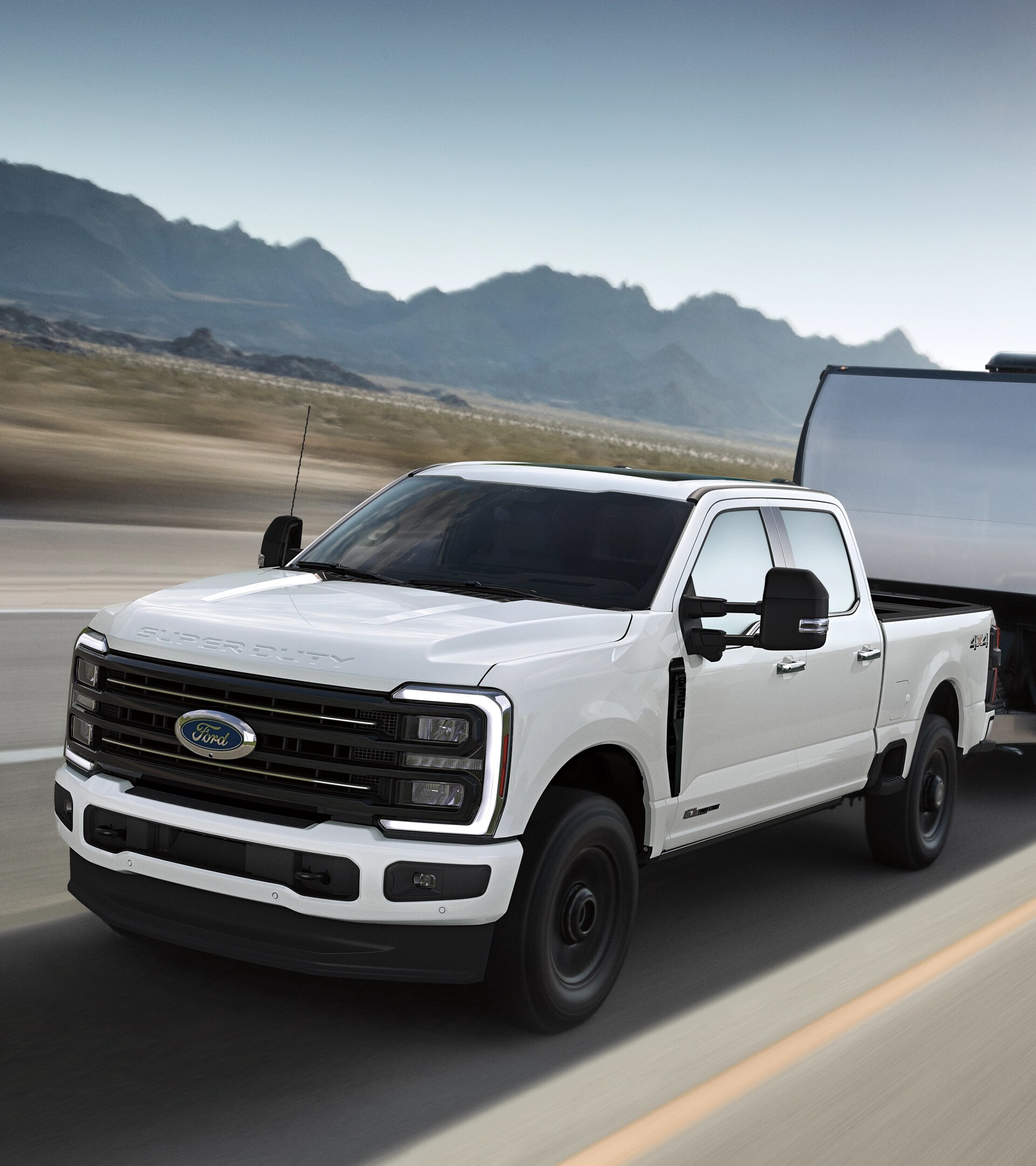 Un modèle Ford Super Duty® F-350® Platinum® 2026 en blanc étoilé avec l’ensemble décor STX tirant une grande remorque.