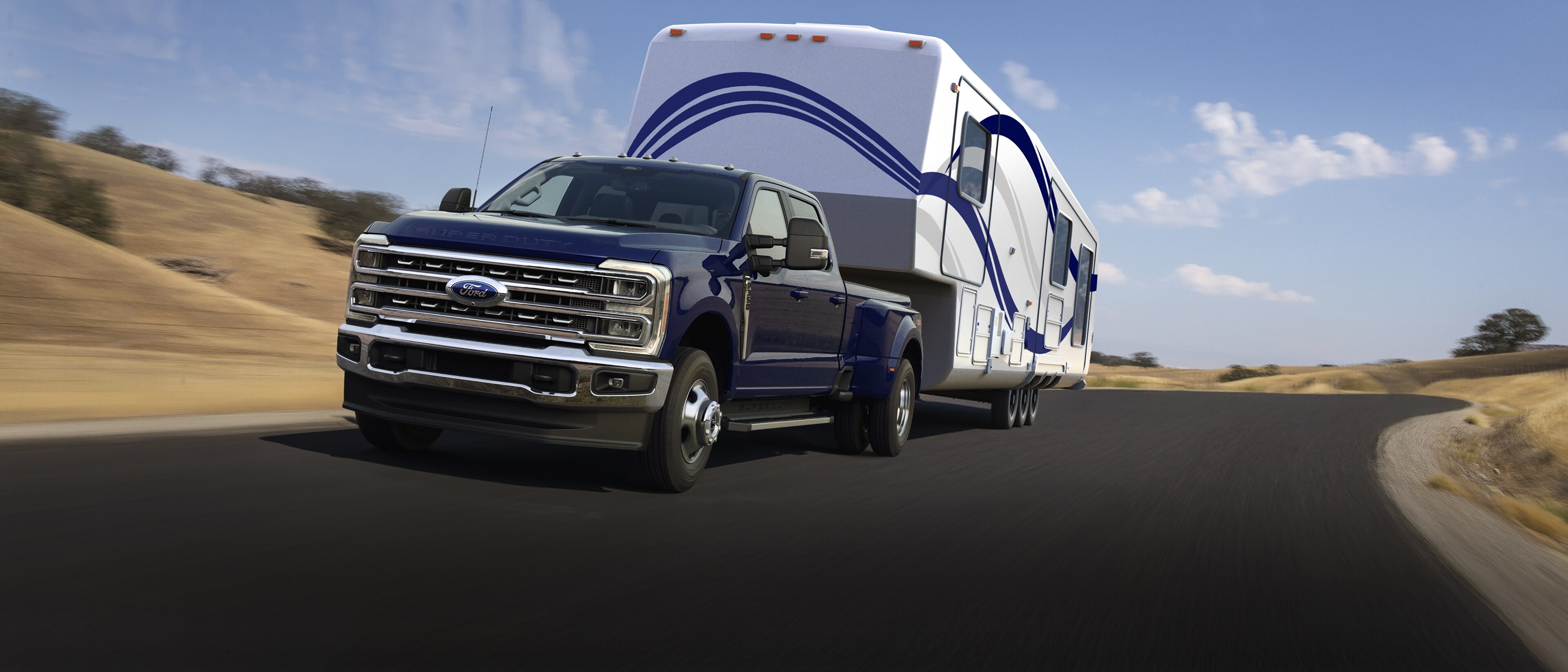Modèle Ford Super Duty® F-250® Lariat® 2026 en bleu argon tirant une grande caravane sur une route pavée