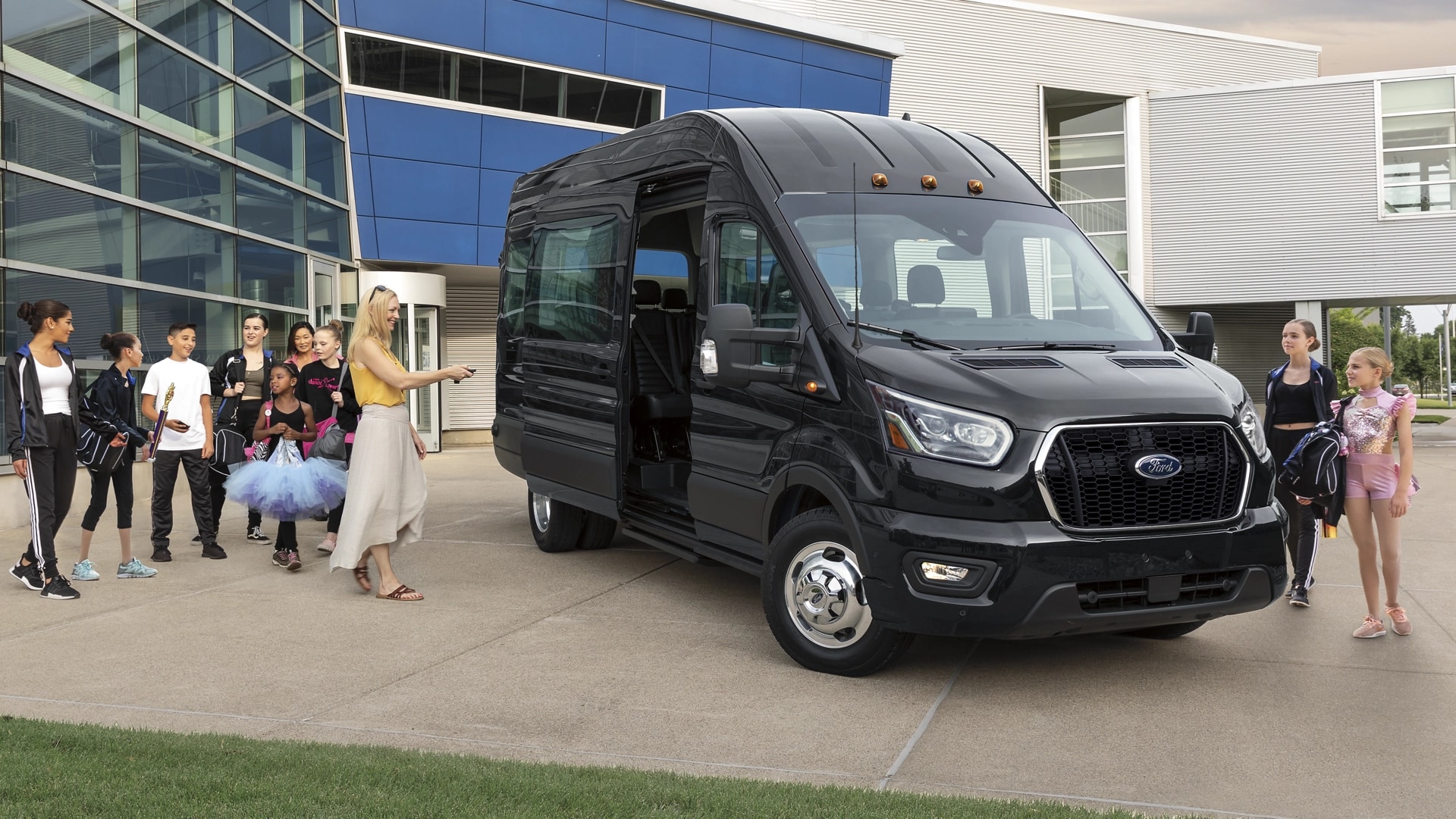 Une fourgonnette Ford Transit® 2025 stationnée avec une femme et de nombreux enfants alentour