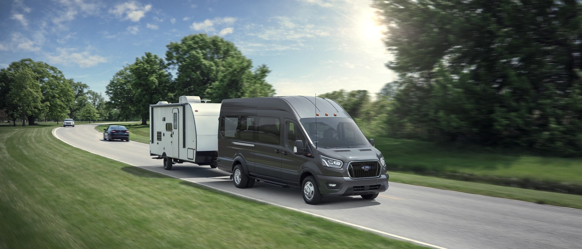 Une fourgonnette Ford Transit® 2025 tirant une remorque sur une route sinueuse