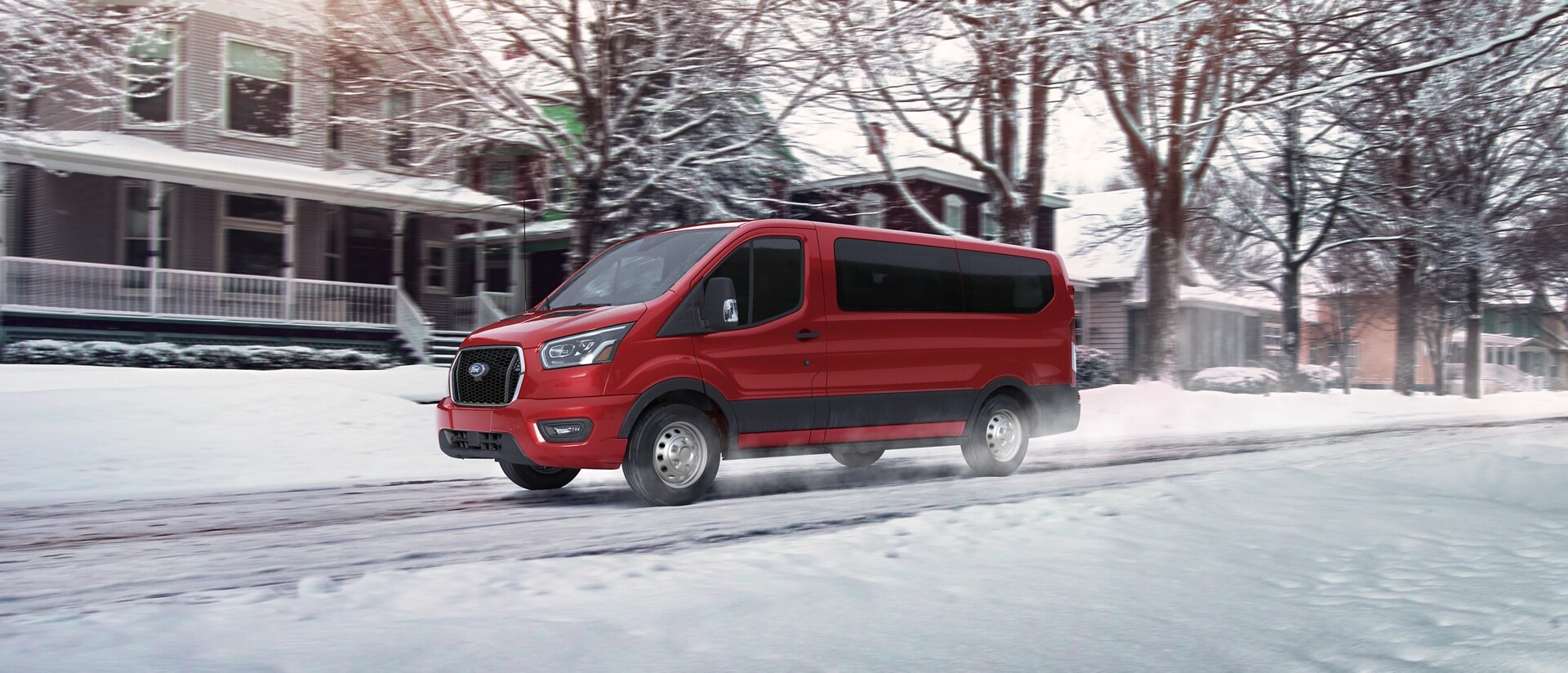 Une fourgonnette Ford Transit® 2025 conduite dans une rue de quartier après une chute de neige