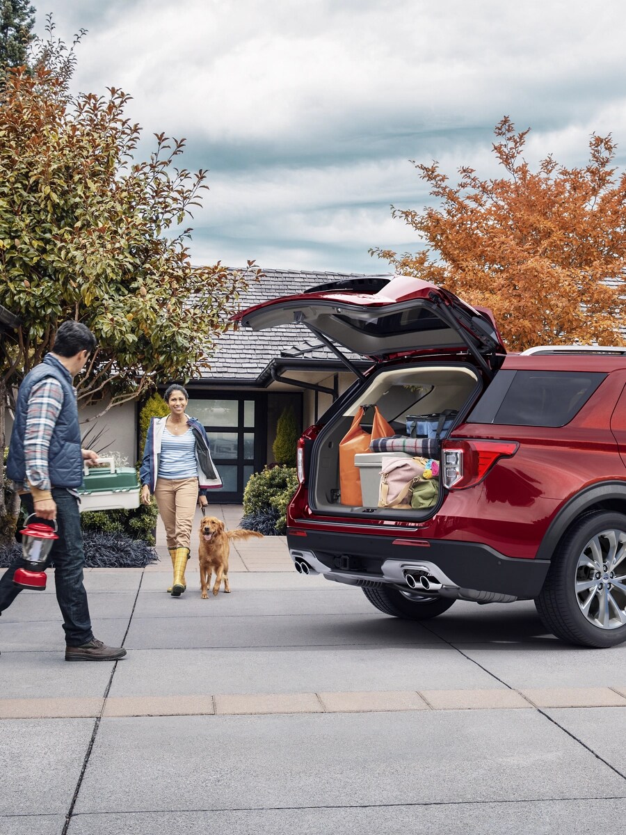Un couple avec un chien marchent vers un VUS Ford