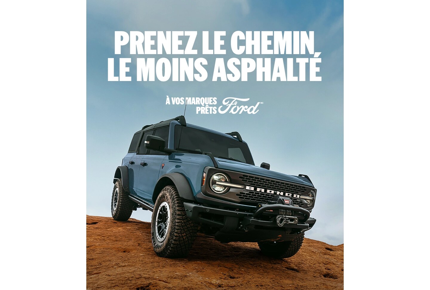 Vue de trois quarts d'un Bronco gris descendant un terrain rocheux.