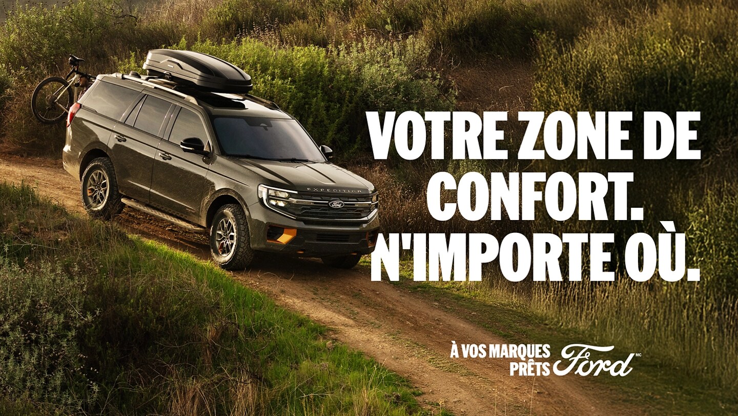 Vue de profil du modèle Expedition 2025 sur un chemin de terre, avec un vélo de montagne monté à l'arrière. Votre zone de confort. N'importe où. À vos marques, prêts, Ford.