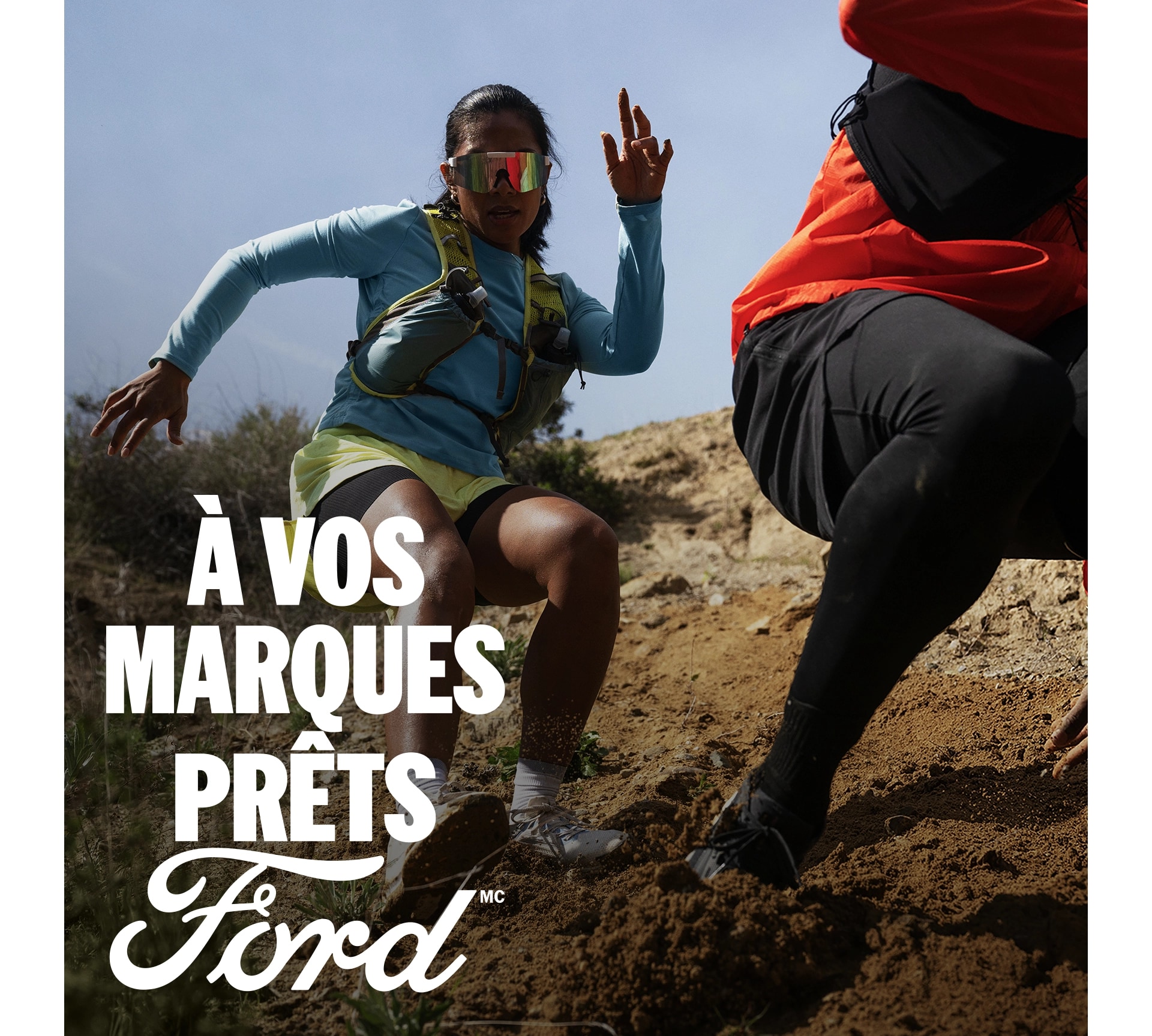 Deux personnes descendant une colline escarpée et boueuse. Le texte blanc « À vos marques. Prêts.Ford » apparaît dans le coin inférieur droit