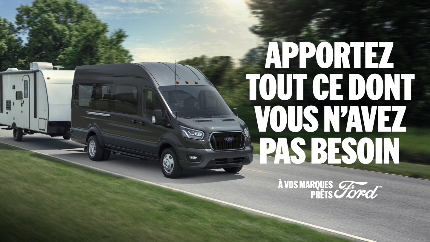 Vue de trois quarts d'un Ford Transit 2025 tractant un camping-car sur une route panoramique. Apportez tout ce dont vous n’avez pas besoin . À vos marques, Prêts, Ford.