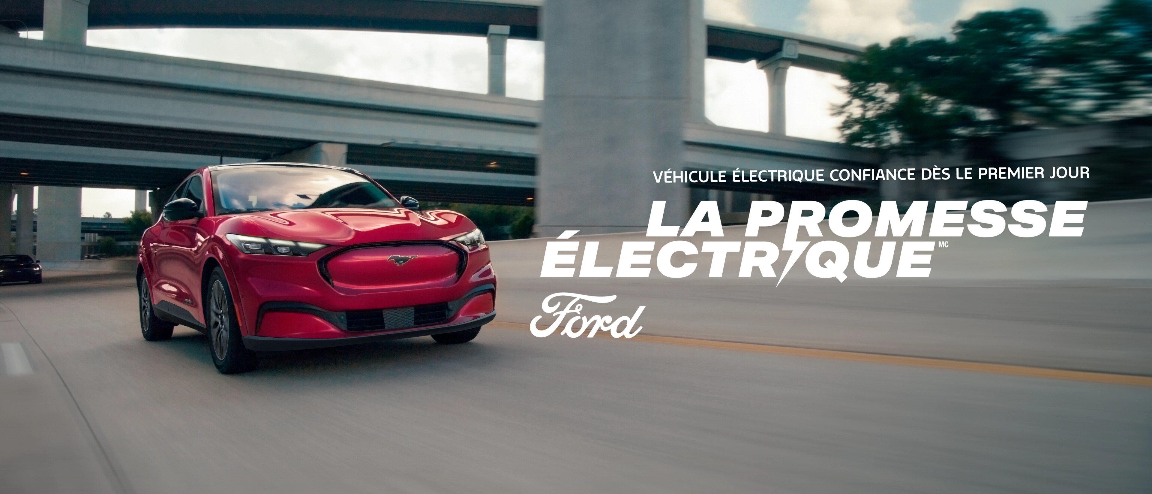 Une Mustang Mach-E rouge circulant sur un autoroute – véhicule électrique confiance dès le premier jour – la promesse électrique Ford
