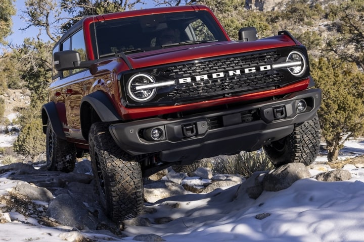 Modèle Ford Bronco® Wildtrak™ 2023 4 portières en rouge course hors route sur un terrain enneigé accidenté