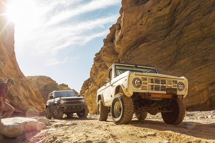 Modèle Ford Bronco® Badlands™ 2023 à 2 portières et Ford Bronco® des années 60 stationné dans un canyon