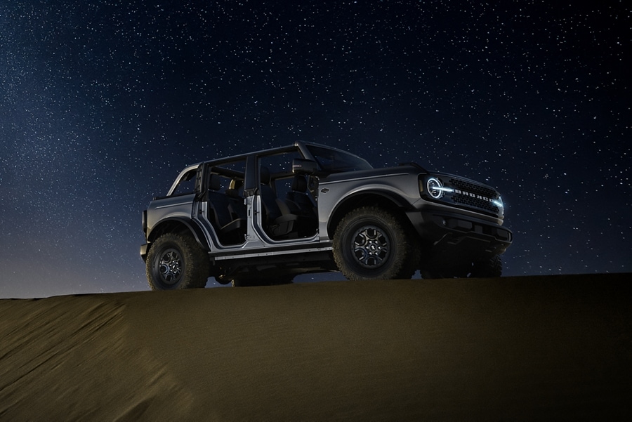 Modèle Ford Bronco® Badlands™ 2023 en gris carbonisé métallisé stationné en pleine nature la nuit