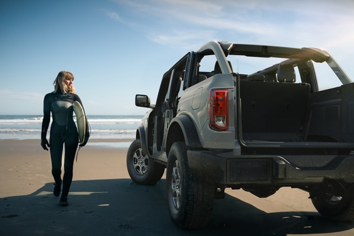 Ford Bronco® 4 portières 2023 en gris cactus avec portières en option et toit retiré stationné sur la plage