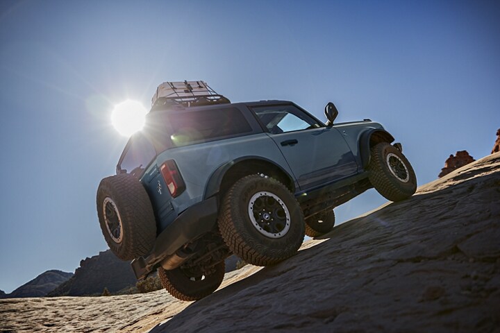Modèle Ford Bronco® Black Diamond™ 2023 2 portières en gris azure à trois couches grimpant sur un terrain accidenté