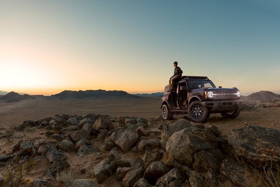 Homme assis sur son VUS Ford Bronco® 2024 au coucher du soleil