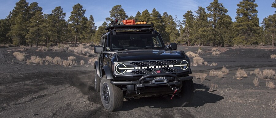 Un Ford Bronco® Badlands™ deux portières 2024 en noir ombre circulant sur un chemin de terre