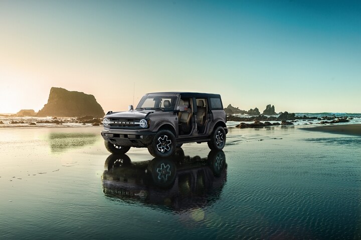 Modèle Ford Bronco® Outer Banks™ 2024 à quatre portières en gris carbonisé métallisé stationné sur le rivage
