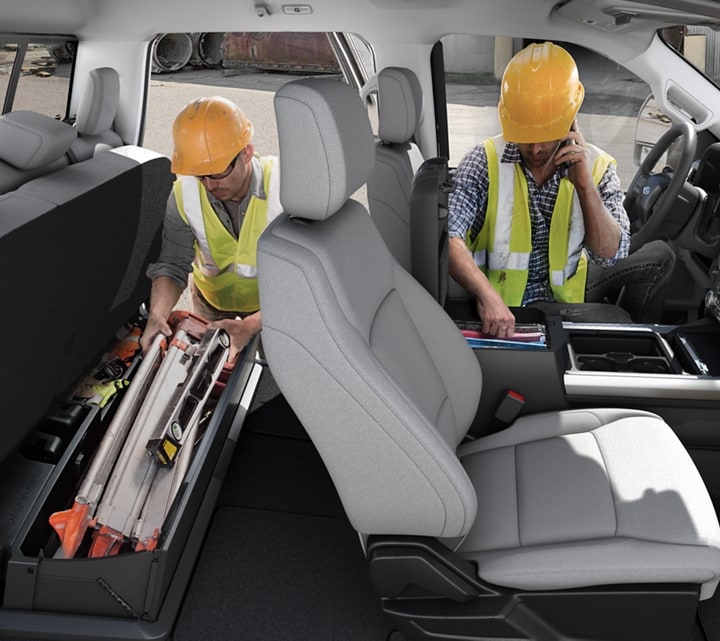 Deux hommes portant un casque de sécurité accèdent aux aires de rangement à l’intérieur de la cabine du Ford Super Duty® à châssis-cabine 2025