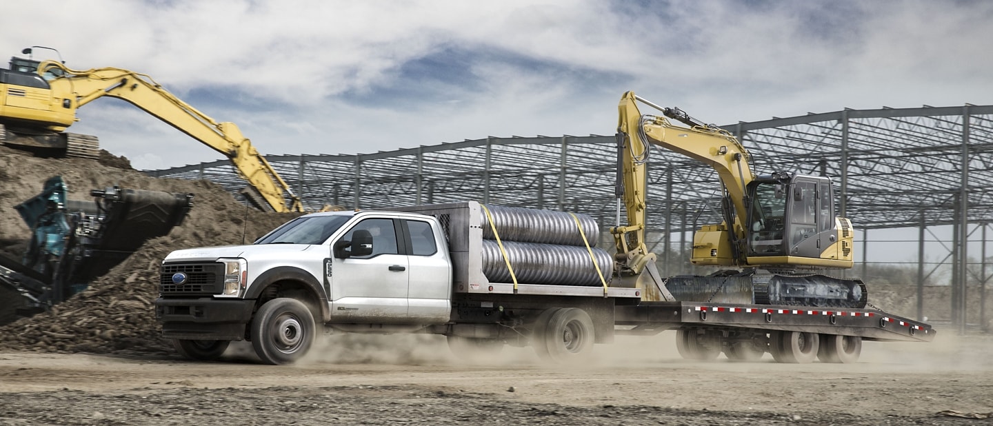 Un Ford F-350® Super Duty® 2025 transportant des tuyaux et faisant une excavatrice