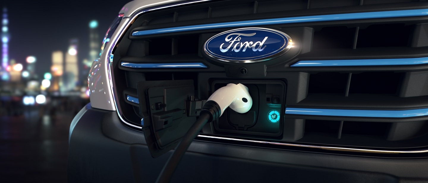 Gros plan de la calandre avec un chargeur branché pour le fourgon Ford E-Transit™ 2023
