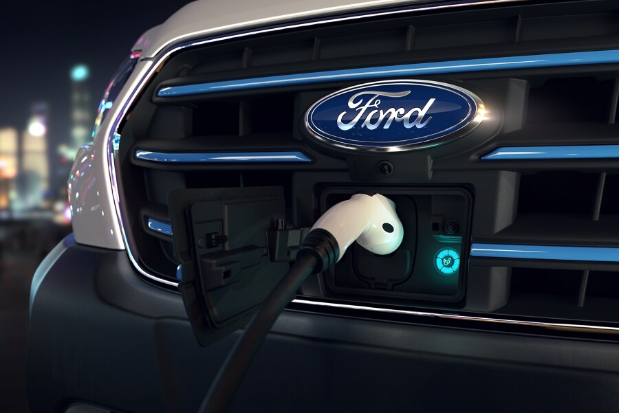 Gros plan sur la calandre du fourgon Ford E-Transit™ 2023 avec le cordon de charge branché
