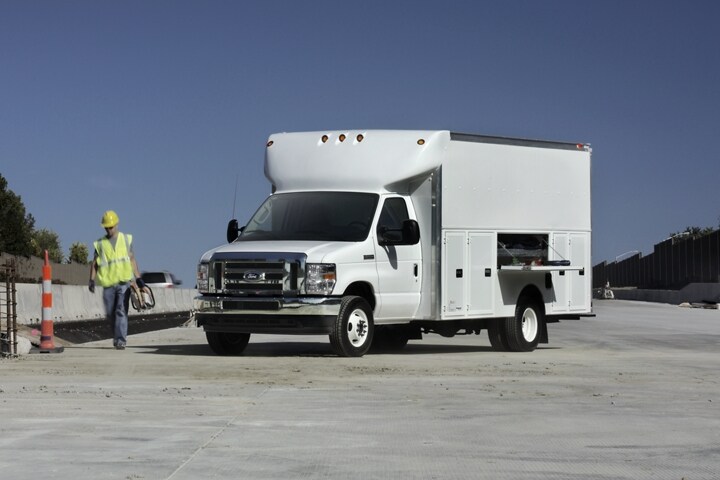 Une personne s’éloignant d’un fourgon tronqué à roues arrière jumelées Ford série E 2025 avec modification de carrosserie d’entrepreneur