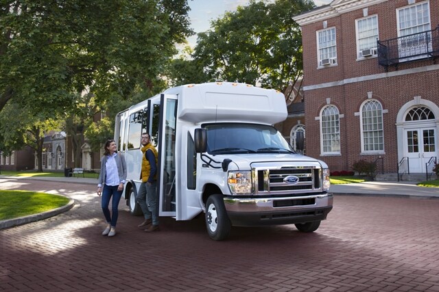 Des gens sortent d’un fourgon tronqué Ford série E 2025 avec carrosserie de bus-navette