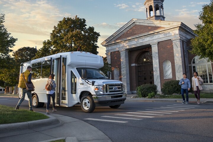 Des personnes montent à bord d’un véhicule tronqué à roues arrière jumelées de la série E de 2025 de Ford avec modification pour bus-navette