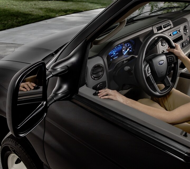 Une femme ajustant les rétroviseurs de remorquage télescopiques en option sur le fourgon tronqué Ford série E 2026